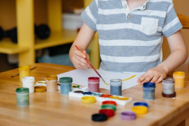 Odasında küçük sevimli bir çocuk oynuyor ve resim yapıyor. Eğlence ve eğlence. Evde kal.