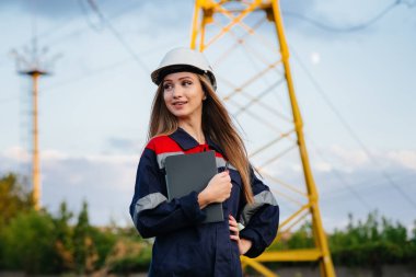 Genç bir mühendis, elektrik hattının ekipmanlarını denetleyip kontrol ediyor. Enerji