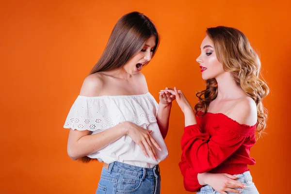 Две Молодые Красивые Девушки Показывают Эмоции Улыбки Студии Оранжевом Фоне — стоковое фото