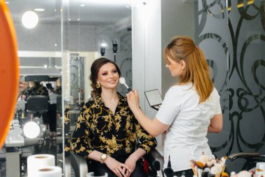 Güzel, modern bir güzellik salonunda, profesyonel bir makyöz genç bir kız için makyaj yapar. Güzellik ve moda.