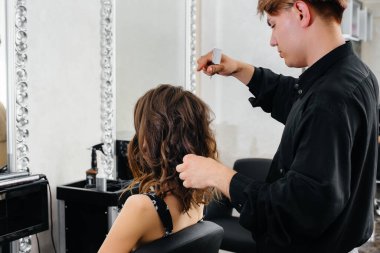 Güzel, modern bir güzellik salonunda, profesyonel bir stilist genç bir kız için saç ve saç kesimi yapar. Güzellik ve moda.