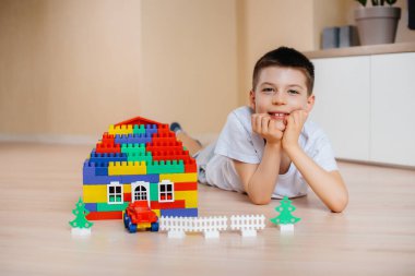 Küçük bir çocuk inşaat setiyle oynuyor ve tüm aile için büyük bir ev inşa ediyor. Bir aile evinin inşaatı.