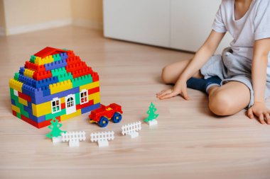 Küçük bir çocuk inşaat setiyle oynuyor ve tüm aile için büyük bir ev inşa ediyor. Bir aile evinin inşaatı.