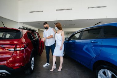 Maskeli genç bir çift yeni bir araç seçiyor ve salgın sırasında bayiliğin temsilcisine danışıyor. Araba satışları ve salgın sırasında hayat.