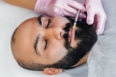 Dudak büyütme ve sakallı bir adam için kırışıklık giderme için estetik ameliyat. Kozmetoloji