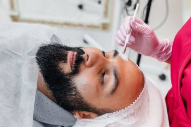 Genç bir adam estetik yüz soyma ameliyatı oluyor. Kozmetoloji ve Gençleştirme