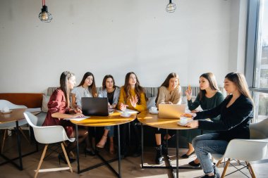 Bir grup genç kız bilgisayarda bir ofiste oturup projeleri tartışıyorlar. İletişim ve eğitim çevrimiçi.