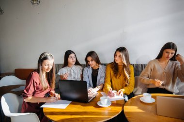 Bir grup genç kız bilgisayarda bir ofiste oturup projeleri tartışıyorlar. İletişim ve eğitim çevrimiçi.