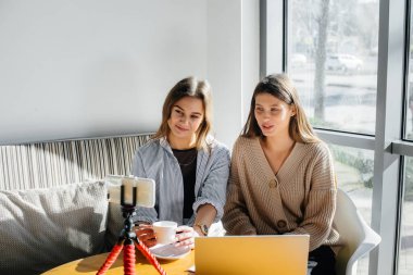 İki güzel kız bir kafede oturup video blogları kaydediyor ve sosyal ağlarda iletişim kuruyor..