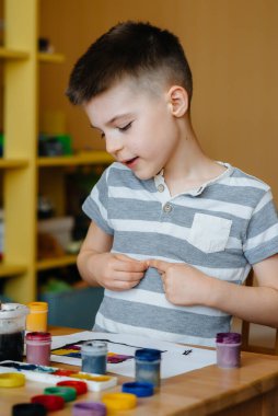 Odasında küçük sevimli bir çocuk oynuyor ve resim yapıyor. Eğlence ve eğlence. Evde kal.