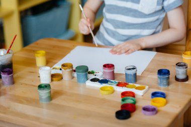 Odasında küçük sevimli bir çocuk oynuyor ve resim yapıyor. Eğlence ve eğlence. Evde kal.