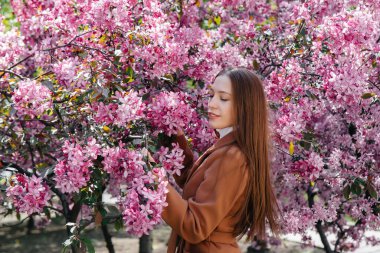 Güzel bir genç kız, bahar günü çiçek açan bir elma bahçesinde yürür. Yaşam tarzı, eğlence.