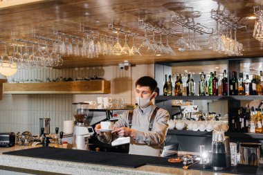 Modern kafede salgın sırasında nefis organik kahve maskeli bir baristanın teslim edilmesi..