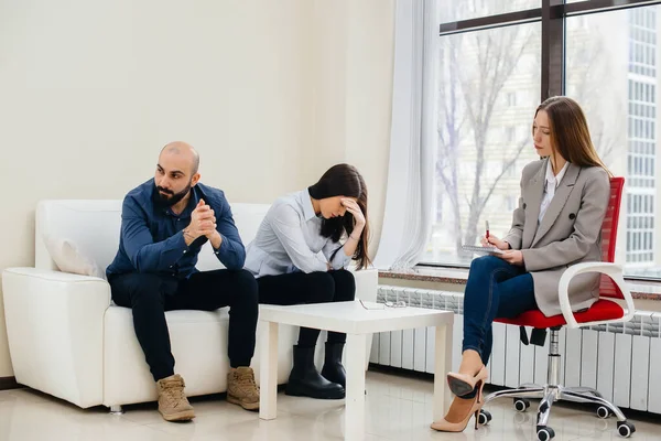 A young married couple of men and women talk to a psychologist at a therapy session. Psychology.