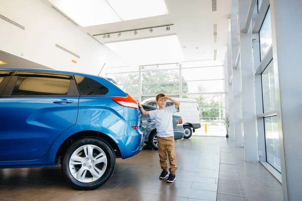 Autokaupassa Iloinen Poika Seisoo Uuden Auton Lähellä Ennen Sen Ostamista — kuvapankkivalokuva
