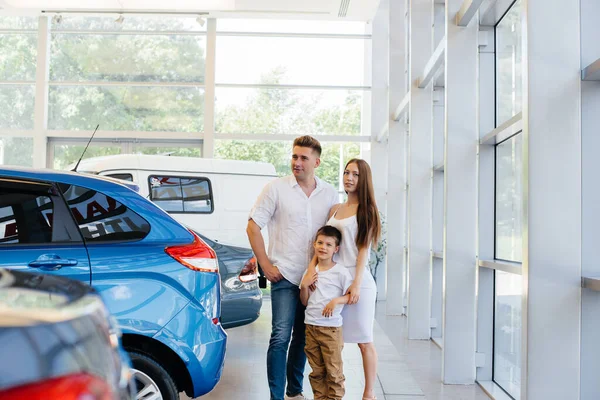 A happy young family chooses and buys a new car at a car dealership. Buying a new car