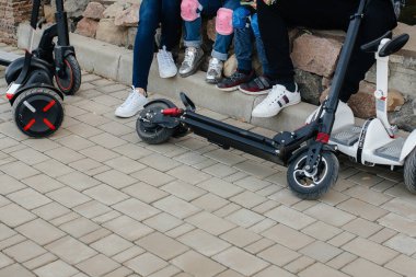 Büyük mutlu bir aile, gün batımında sıcak bir sonbahar gününde Segways ve elektrikli scooter kullanır. Park 'ta aile tatili.
