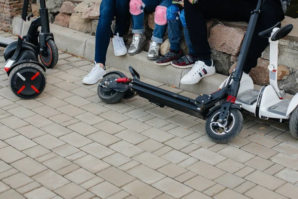 Büyük mutlu bir aile, gün batımında sıcak bir sonbahar gününde Segways ve elektrikli scooter kullanır. Park 'ta aile tatili.