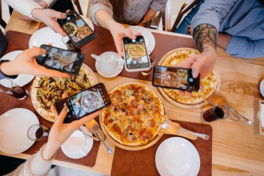Bir grup arkadaş, blog için lezzetli bir pizzanın yakın plan fotoğrafını çekiyor: Pizzacı..