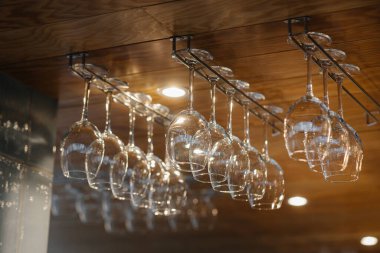 Modern bir restoranda barın üzerinde alkollü içecekler için temiz bardaklar asılı..