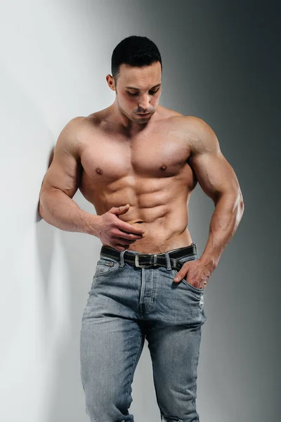 Jeune Bodybuilder Athlète Pose Studio Seins Nus Jeans Près Mur — Photo