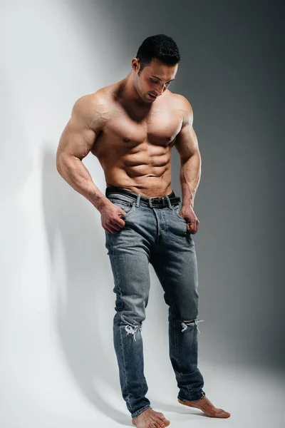 Jeune Bodybuilder Athlète Pose Studio Seins Nus Jeans Près Mur — Photo