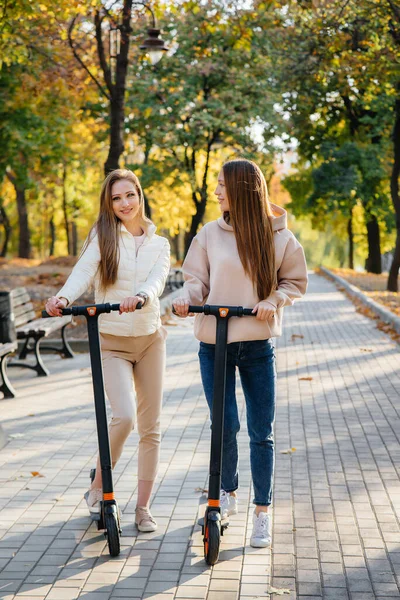 Két Fiatal Gyönyörű Lány Elektromos Robogózik Parkban Egy Meleg Őszi — Stock Fotó