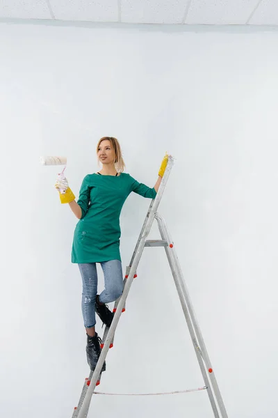 Una Joven Sobre Una Escalera Pinta Una Pared Blanca Con — Foto de Stock