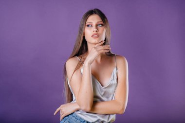 Genç ve güzel bir kız, mor bir arka planda stüdyoda duygularını ve gülümsemelerini gösterir. Reklam için kızlar