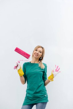 Genç bir kız beyaz bir duvar boyamadan önce pembe bir silindirle poz veriyor. İç kısmın tamiri.