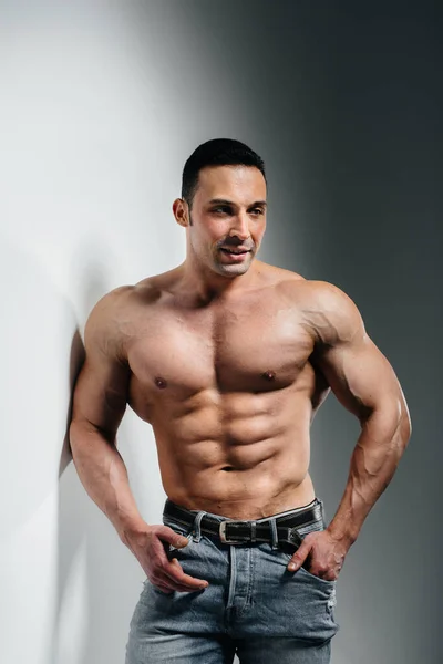 Jeune Bodybuilder Athlète Pose Studio Seins Nus Jeans Près Mur — Photo