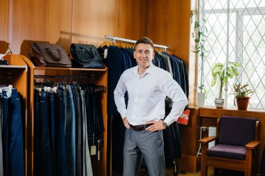 Genç bir adam alışverişe gider ve bir erkeğin takım elbisesini alır..