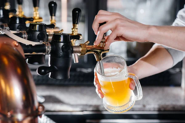 Close-up of the bartender filling a mug of light beer. The bar counter in the pub.