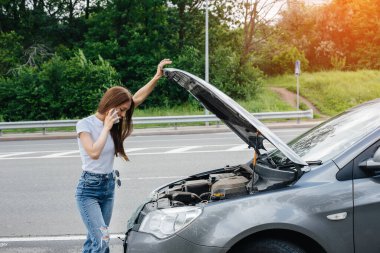 Genç bir kız otoyolun ortasında bozuk bir arabanın yanında duruyor ve telefondan yardım istiyor. Aracın bozulması ve arızası. Yardım bekliyorum..
