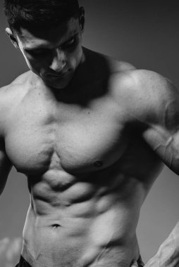 Mükemmel karın kasları olan genç seksi bir sporcu stüdyoda üstsüz poz veriyor. Sağlıklı yaşam tarzı, düzgün beslenme, eğitim programları ve kilo vermek için beslenme. Siyah ve beyaz.