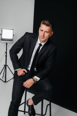 Siyah takım elbiseli yakışıklı bir genç siyah arka planda poz veriyor. Şık bir iş adamı. Büyük bir iş adamı..