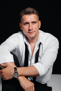 Beyaz gömlekli şık bir genç adam siyah arka planda yönetmen koltuğunda oturuyor. Yakışıklı, karizmatik bir iş adamı..