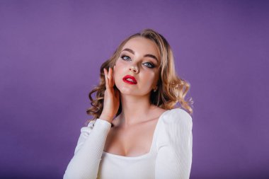 Genç ve güzel bir kız, mor bir arka planda stüdyoda duygularını ve gülümsemelerini gösterir. Reklam için kızlar