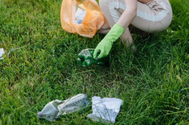 Gün batımında çocuklu bir grup kız parkta çöp toplamakla meşgul. Çevre bakımı, geri dönüşüm.