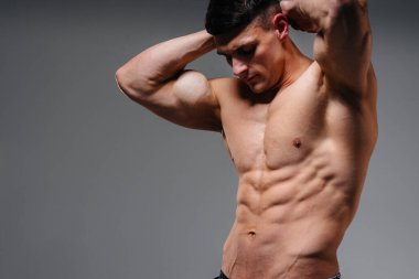 Mükemmel karın kasları olan genç seksi bir sporcu arka planda kot pantolonla stüdyoda üstsüz poz veriyor. Sağlıklı yaşam tarzı, düzgün beslenme, eğitim programları ve kilo vermek için beslenme.