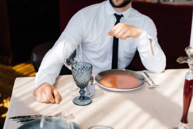 Genç sakallı bir erkek işadamı iyi bir restoranda bir masada oturuyor ve emirlerini bekliyor. Yemek şirketinde müşteri hizmetleri..