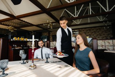 Şık bir garson, bir gurme restoranında randevuya gelen genç bir çifte servis yapar. Yemek şirketinde müşteri hizmetleri..