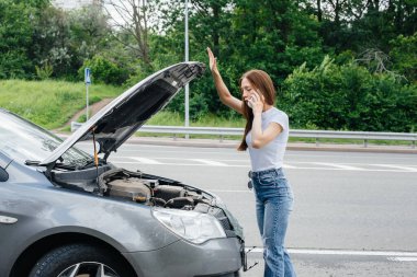 Genç bir kız otoyolun ortasında bozuk bir arabanın yanında duruyor ve telefondan yardım istiyor. Aracın bozulması ve arızası. Yardım bekliyorum..