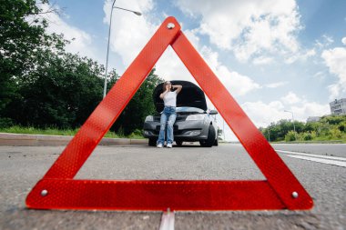 Genç bir kız otoyolun ortasında bozuk bir arabanın yanında duruyor ve telefondan yardım istiyor. Aracın bozulması ve arızası. Yardım bekliyorum..