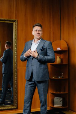 Genç bir adam mağazanın soyunma odasında yeni bir takım elbise deniyor..