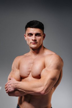 Mükemmel karın kasları olan genç seksi bir sporcu arka planda kot pantolonla stüdyoda üstsüz poz veriyor. Sağlıklı yaşam tarzı, düzgün beslenme, eğitim programları ve kilo vermek için beslenme.