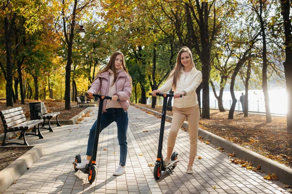 Két Fiatal Gyönyörű Lány Elektromos Robogózik Parkban Egy Meleg Őszi — Stock Fotó