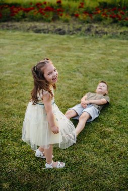 Erkek ve kız kardeş gün batımında parkta çimlerin üzerinde koşar, oynar ve eğlenirler. Mutlu çocukluk.