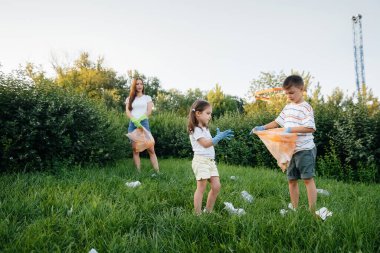 Gün batımında çocuklu bir grup kız parkta çöp toplamakla meşgul. Çevre bakımı, geri dönüşüm.
