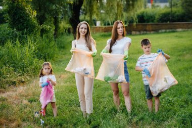 Gün batımında çocuklu bir grup kız parkta çöp toplamakla meşgul. Çevre bakımı, geri dönüşüm.